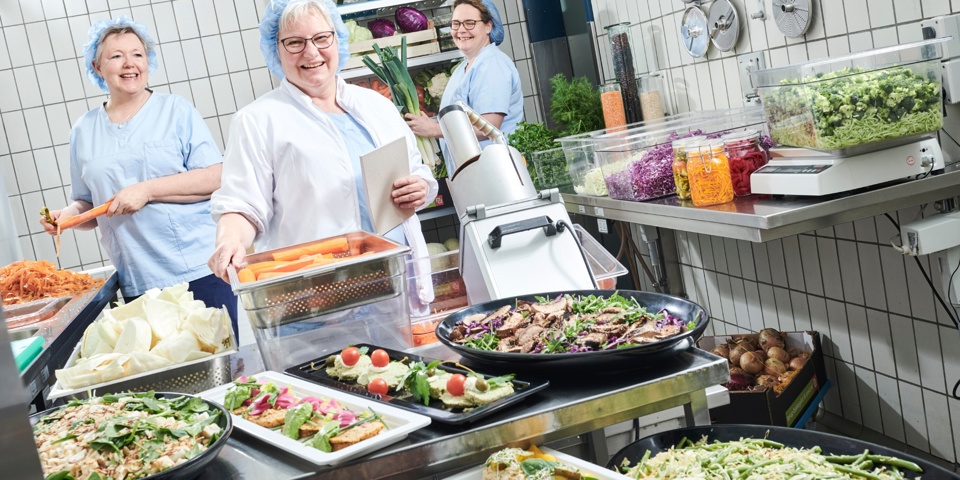 Her ses fra venstre ernæringsassistent Kate Kjellerup, køkkenchef Vibeke Jochumsen og ernæringsassistent Mette Pilgaard Skovbjerg omgivet af farvestrålende retter i køkkenet på Esbjerg og GrindstedSygehus.