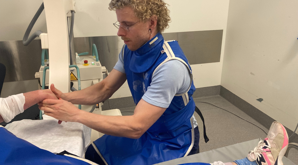 Lægen Rune Wiig Nielsen holder om en patients håndled, imens patienten ligger på en brik.