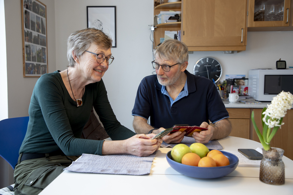 Ægtepar sidder ved køkkenbord og koordinerer deres kalendre