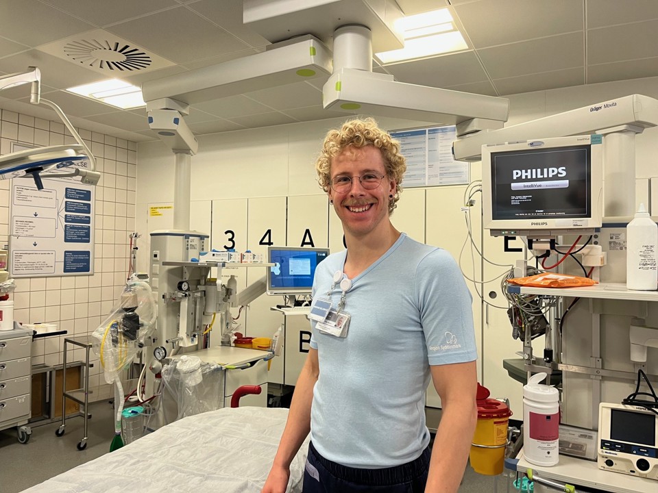 Introlæge Rune Wiig Nielsen står omgivet af briks og maskiner i en af skadestuens traumestuer.