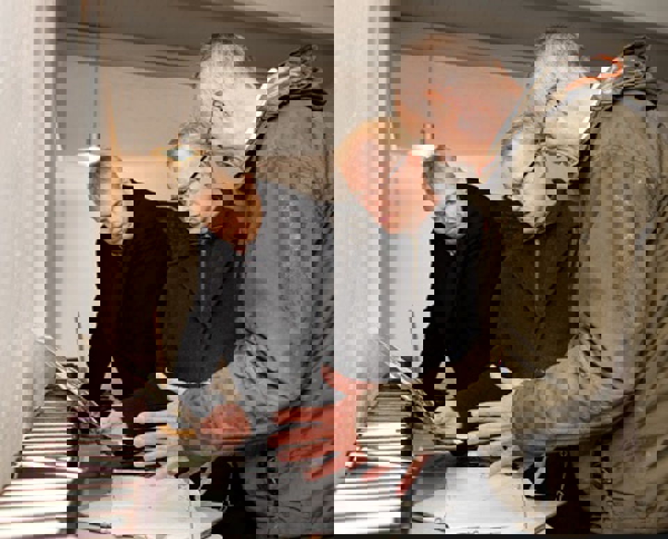 Regionsrådsformand Carl Holst sammen med Steen Wulff Andersen og Ove Sørensen.  Museumsleder Ove Sørensen, Carl Holst og Steen Wulff  Andersen er krøbet i læ for regnen i Jelling Kirkes våbenhus  for at se på skitser over udgravningerne.