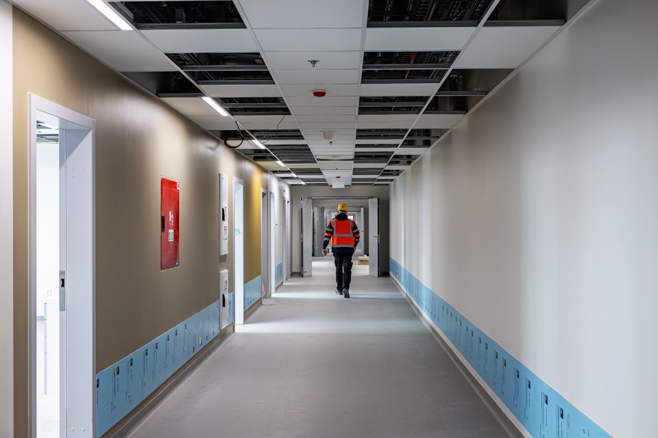 Billede af ryggen af en medarbejder, der går ned ad en hospitalsgang på det nye OUH. 