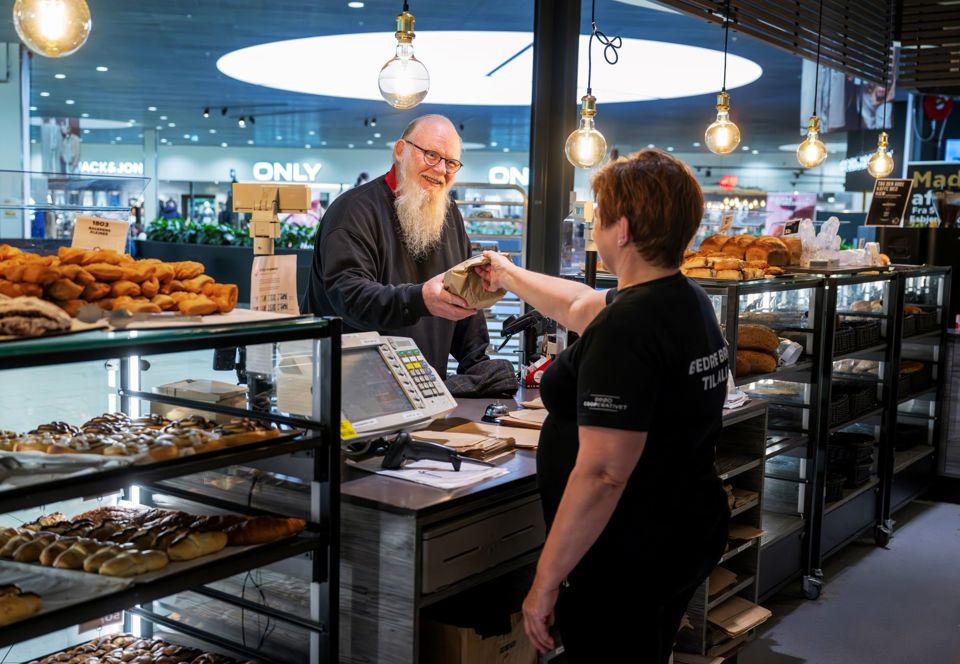 Mand med langt hvidt skæg køber et brød hos bageren.