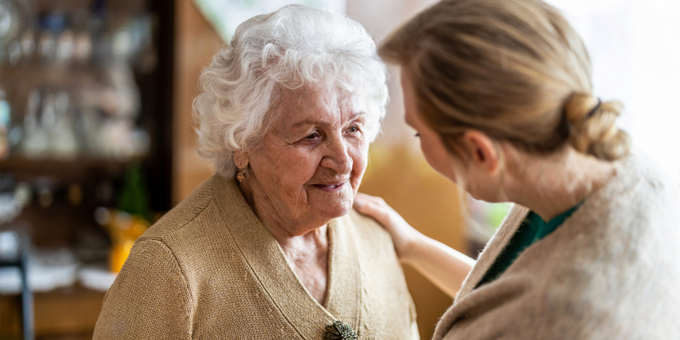 Sygeplejerske taler med ældre kvinde.