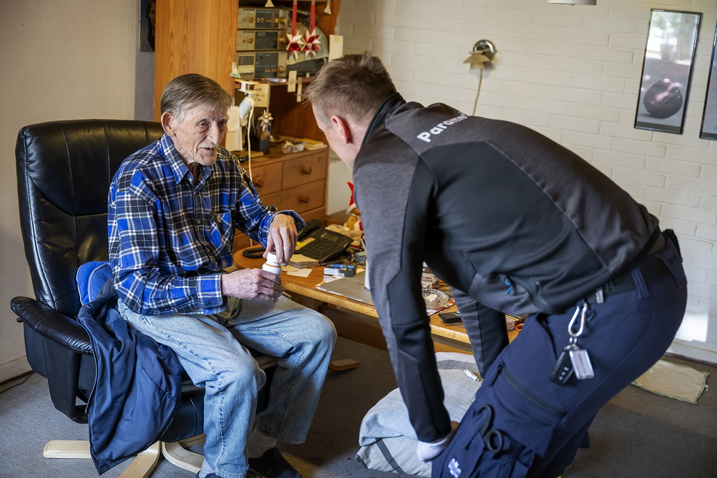 Billede af ældre mand, der får besøg af paramediciner.
