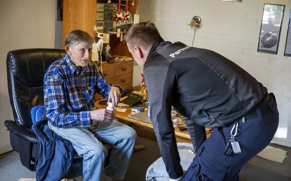 Billede af ældre mand, der får besøg af paramediciner.