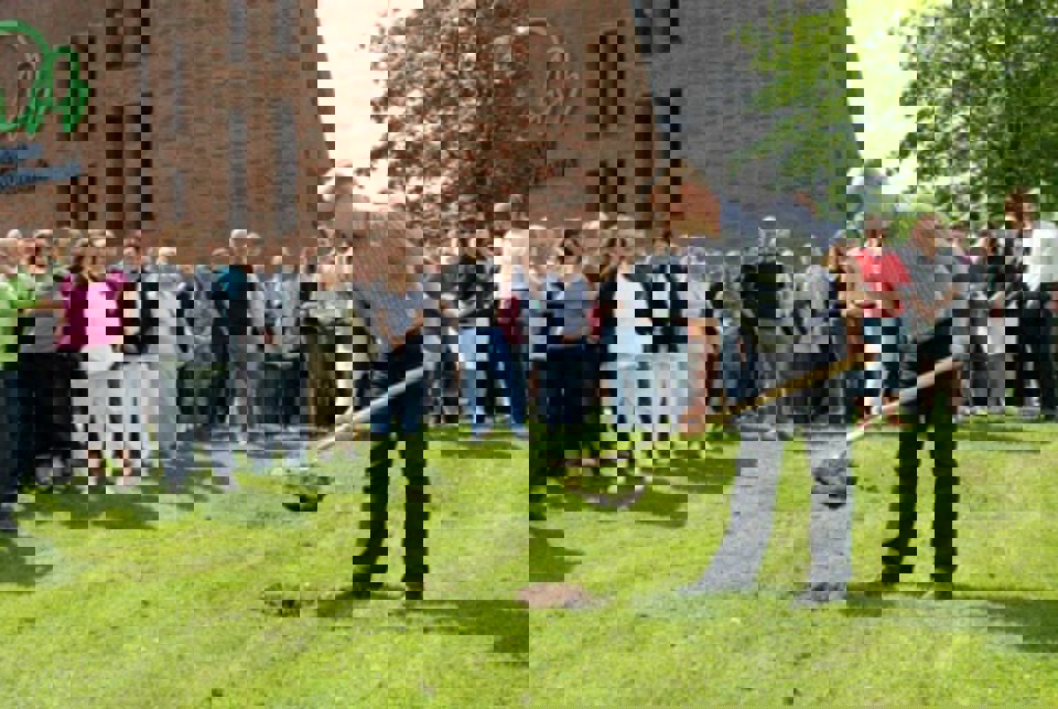 Medarbejderne ser til, mens regionsrådsformand Carl Holst tager det første spadestik til udvidelsen af deres arbejdsplads. 