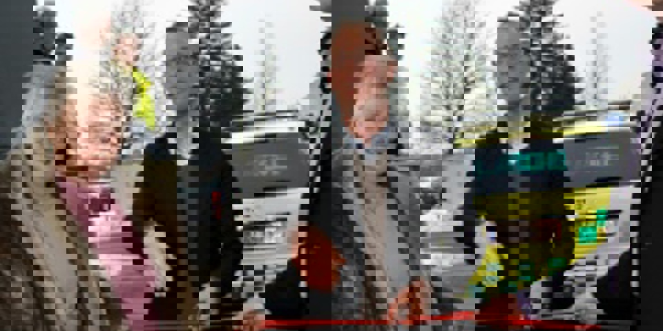 Regionsrådsformand Carl Holst (V) klipper snoren  over med et værktøj fra lægebilens taske.  En form for kniv, som bl.a. kan bruges til at klippe  sikkerhedsseler over med. Her ses han sammen  med borgmester i Kolding Kommune, Jørn Pedersen,  samt praktiserende læge Jytte Frøkjær. Det er  hende, der tidligere har kørt lægebilen fra sin  praksis i Lunderskov.