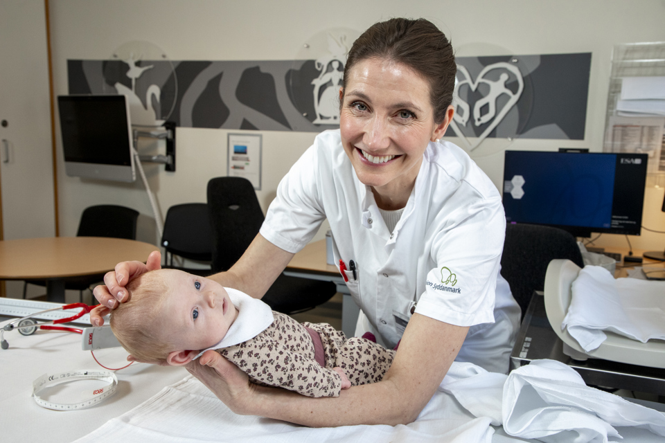 Kvindelig børnelæge med lille barn i hænderne.