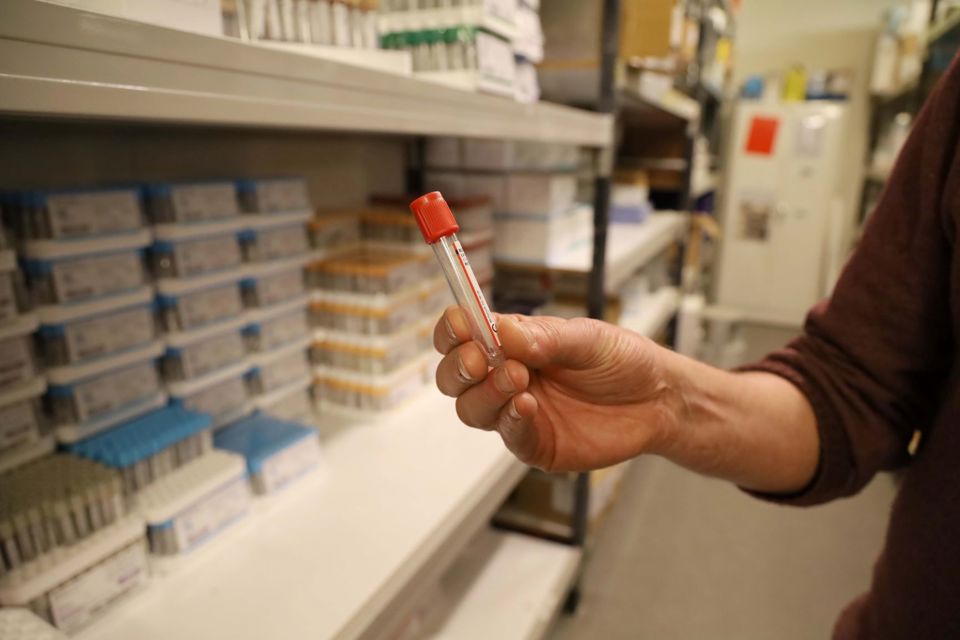 En hånd viser et blodprøverør frem.