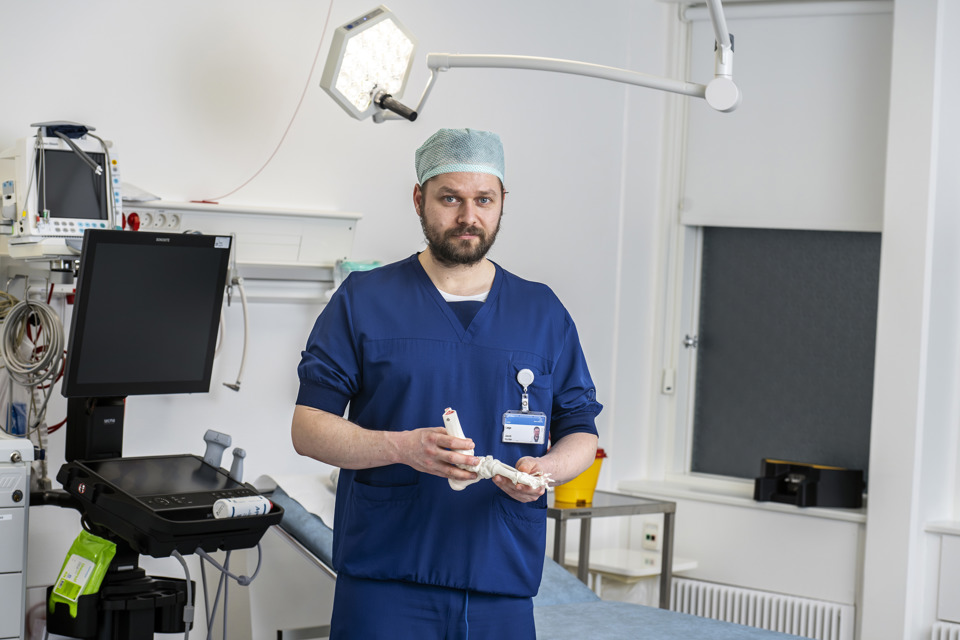 Mandlig læge i blåt operationstøj stående på operationsstue.