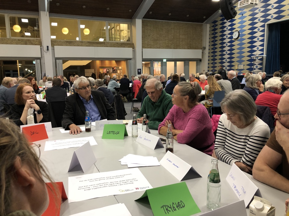 Borgere sidder om et bord og taler sammen.
